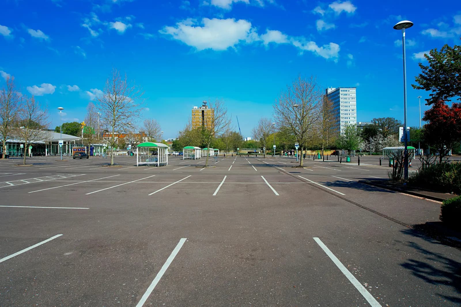 Large parking lot with white space markings under a clear blue sky